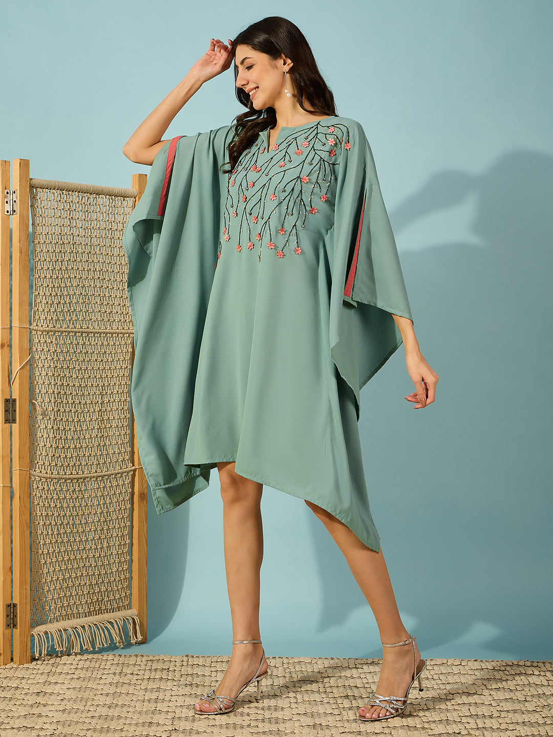 Green party kaftan dress featuring delicate bead embroidery and stunning pink floral embellishments.
