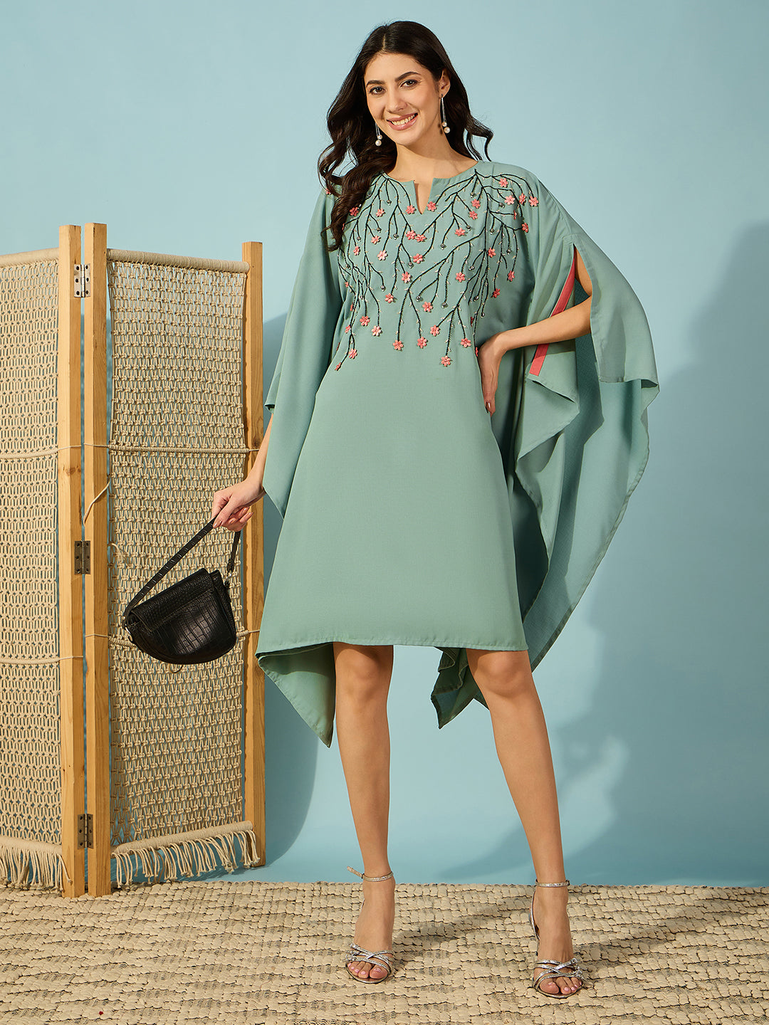 Elegant green embroidered kaftan dress with intricate black beadwork and pink floral accents.
