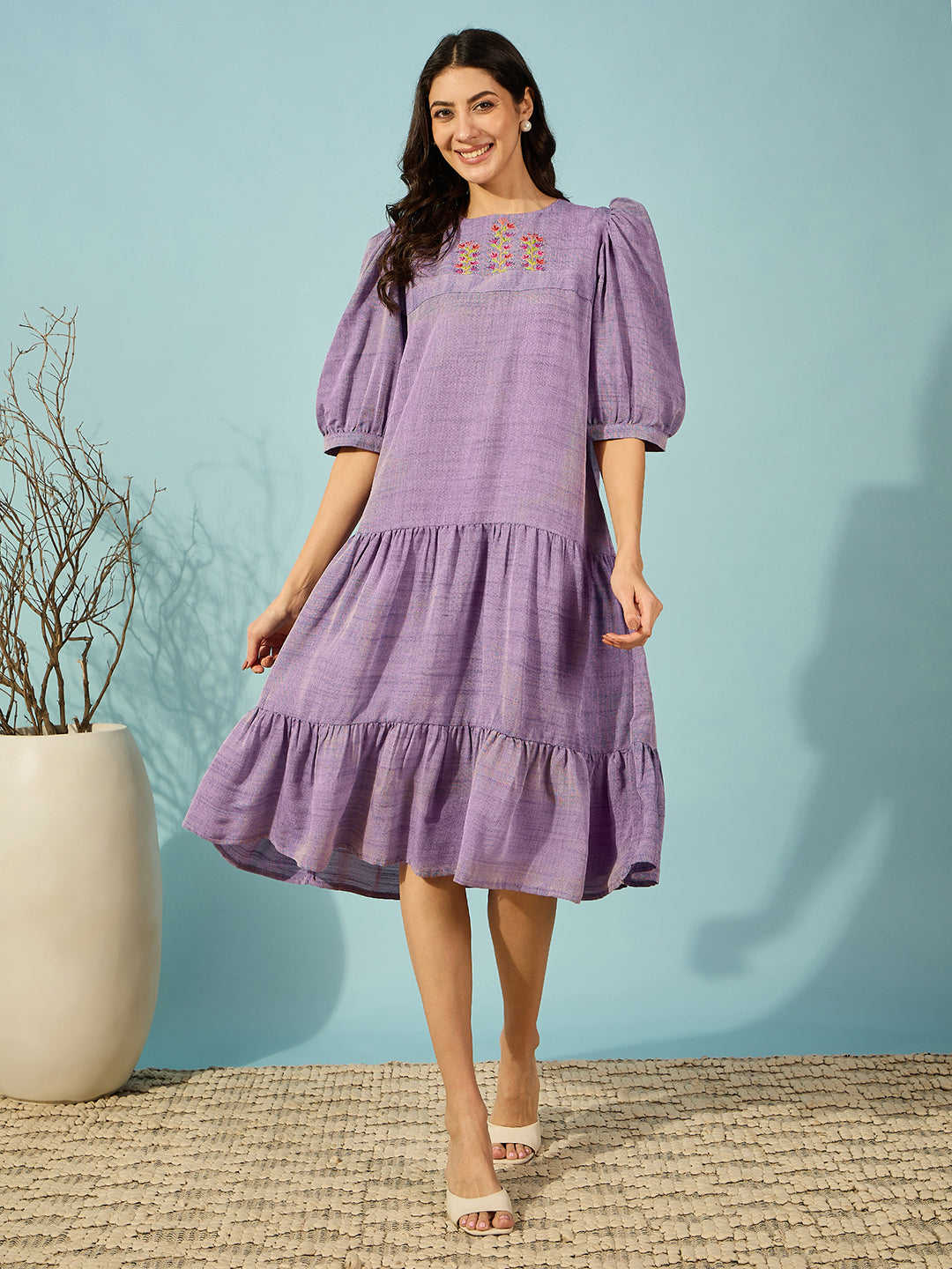 Elegant purple viscose linen knee length dress with intricate hand embroidery and puffed sleeves.
