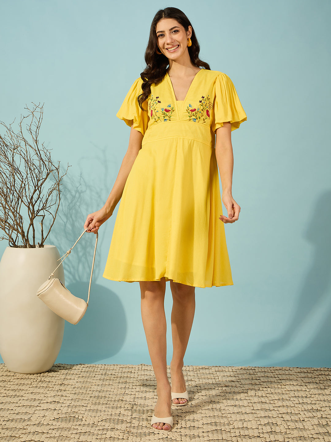 Women's yellow knee-length dress crafted from viscose linen with elegant hand embroidery accents.
