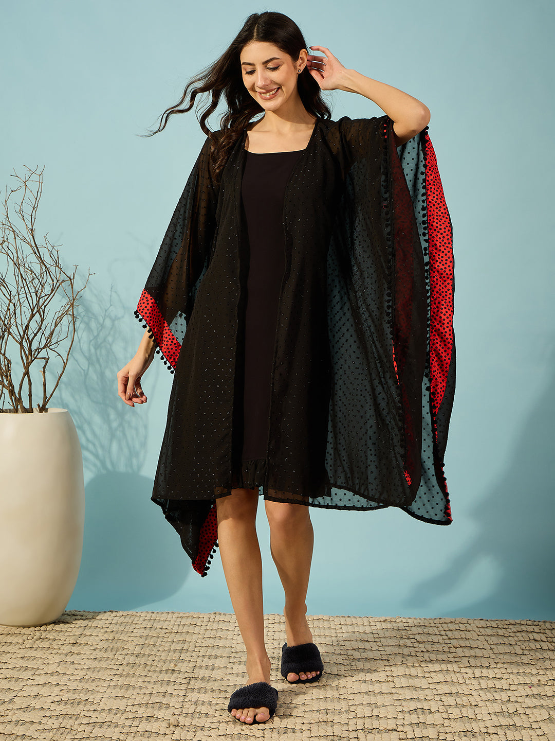 Elegant black georgette gown set with a red polka border, featuring a ruffled lace hem.
