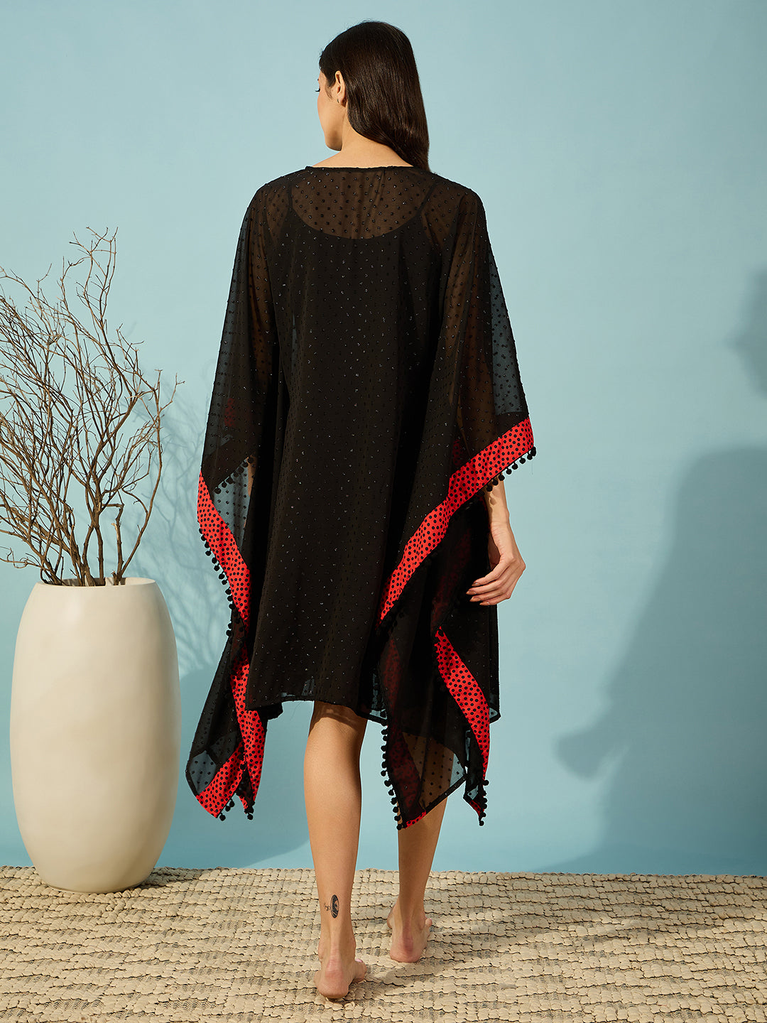 Feminine black gown with ruffle lace hem and bold red polka detailing.
