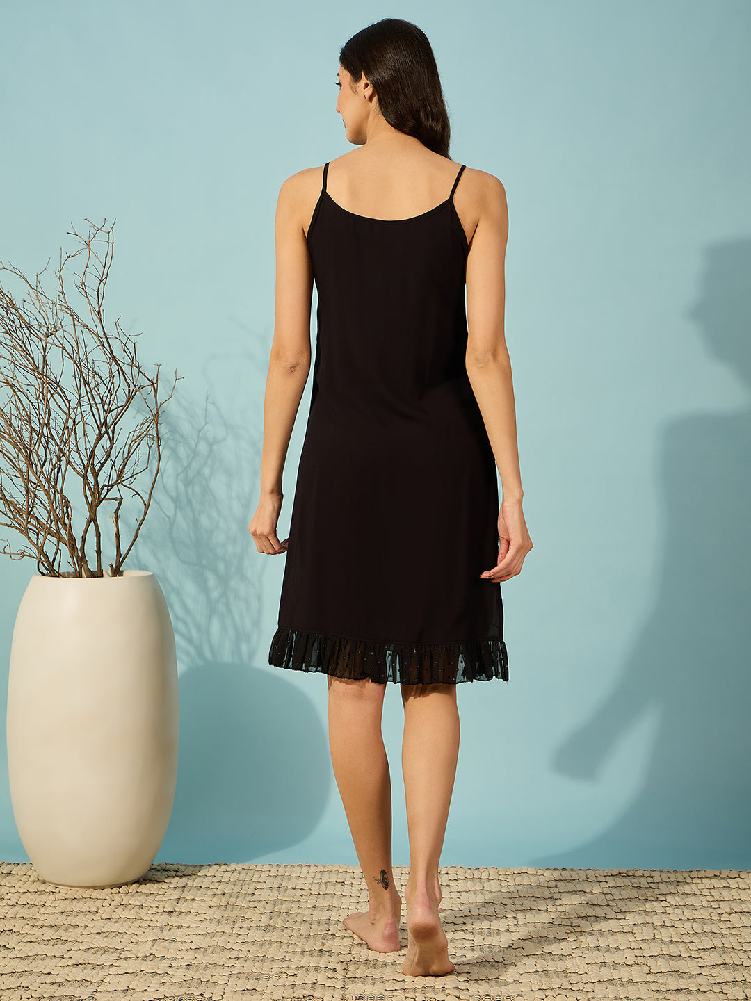 Womenâ€™s black georgette gown with a red polka border and delicate lace ruffle detail.
