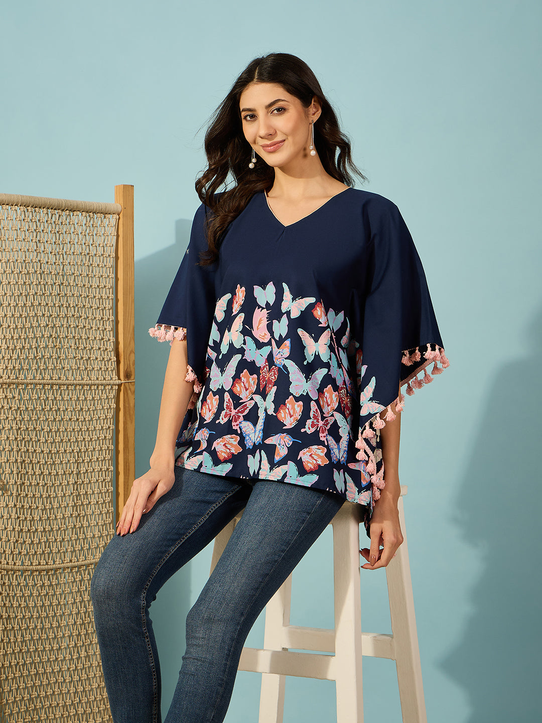Slim-fit blue cotton kaftan top with vivid butterfly print and detailed tassel accents.
