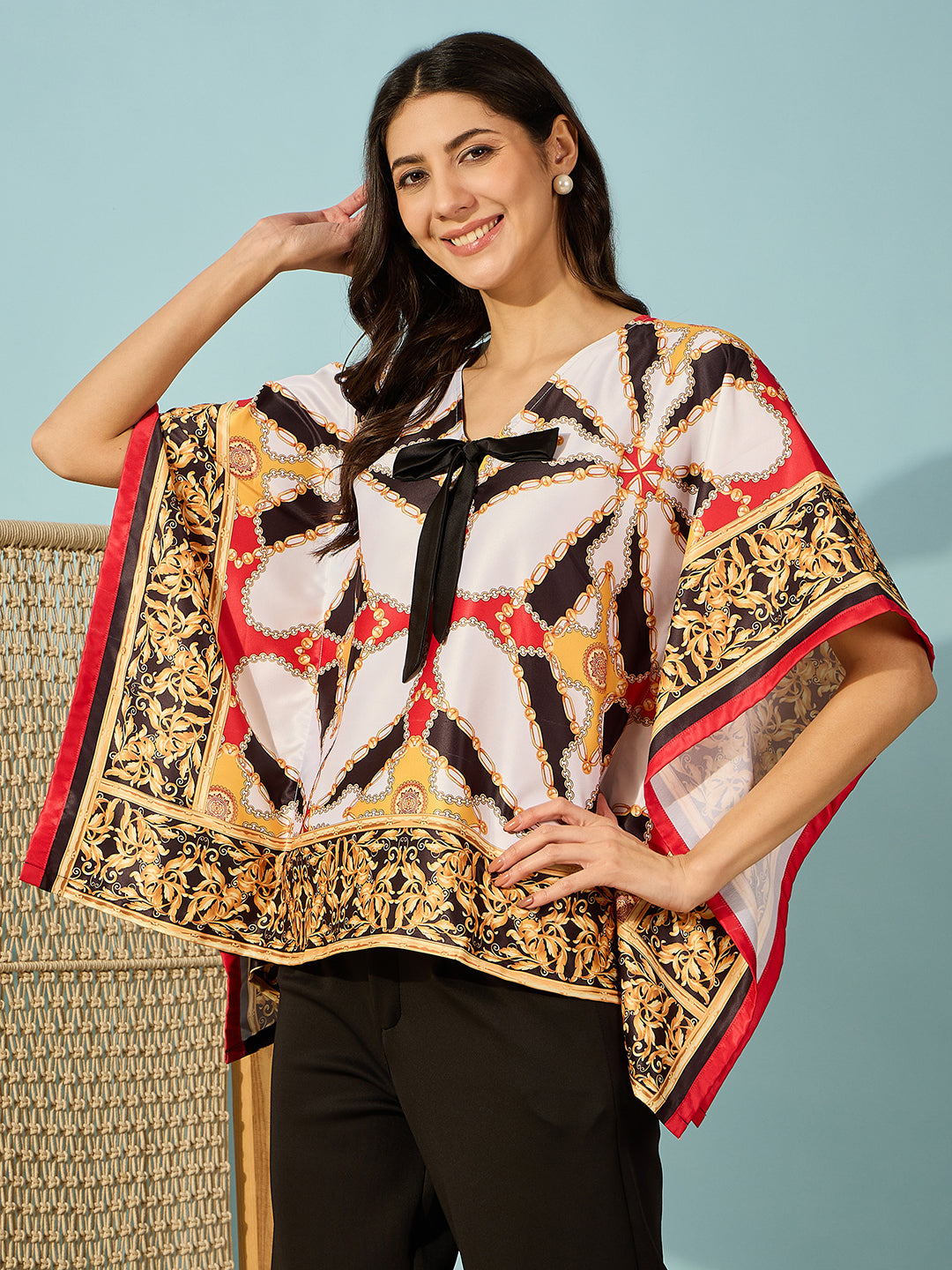 Sleek black satin kaftan top with bold Baroque pattern and bow accent.
